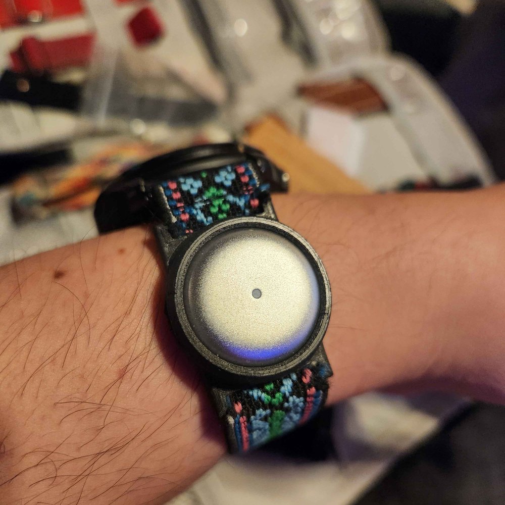 Omi disc in a hand-woven wristband, worn on the arm